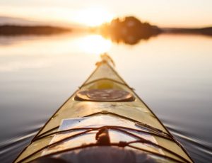 Kayak pointing to the sun on a calm body of water