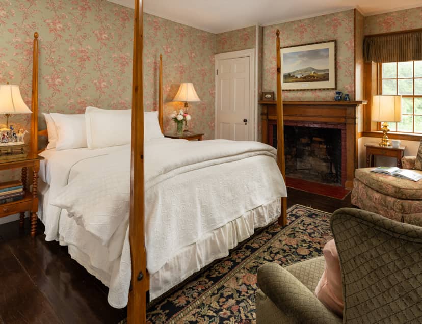 Room 11 with a king-size four poster bed a fireplace and large area rug on wood floors