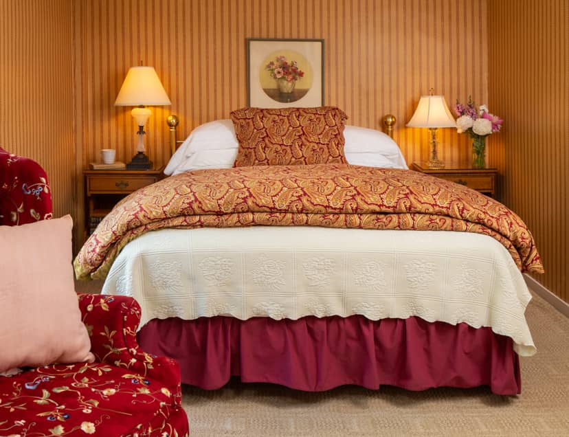 Room 7 with a queen bed carpet flooring and a red chair