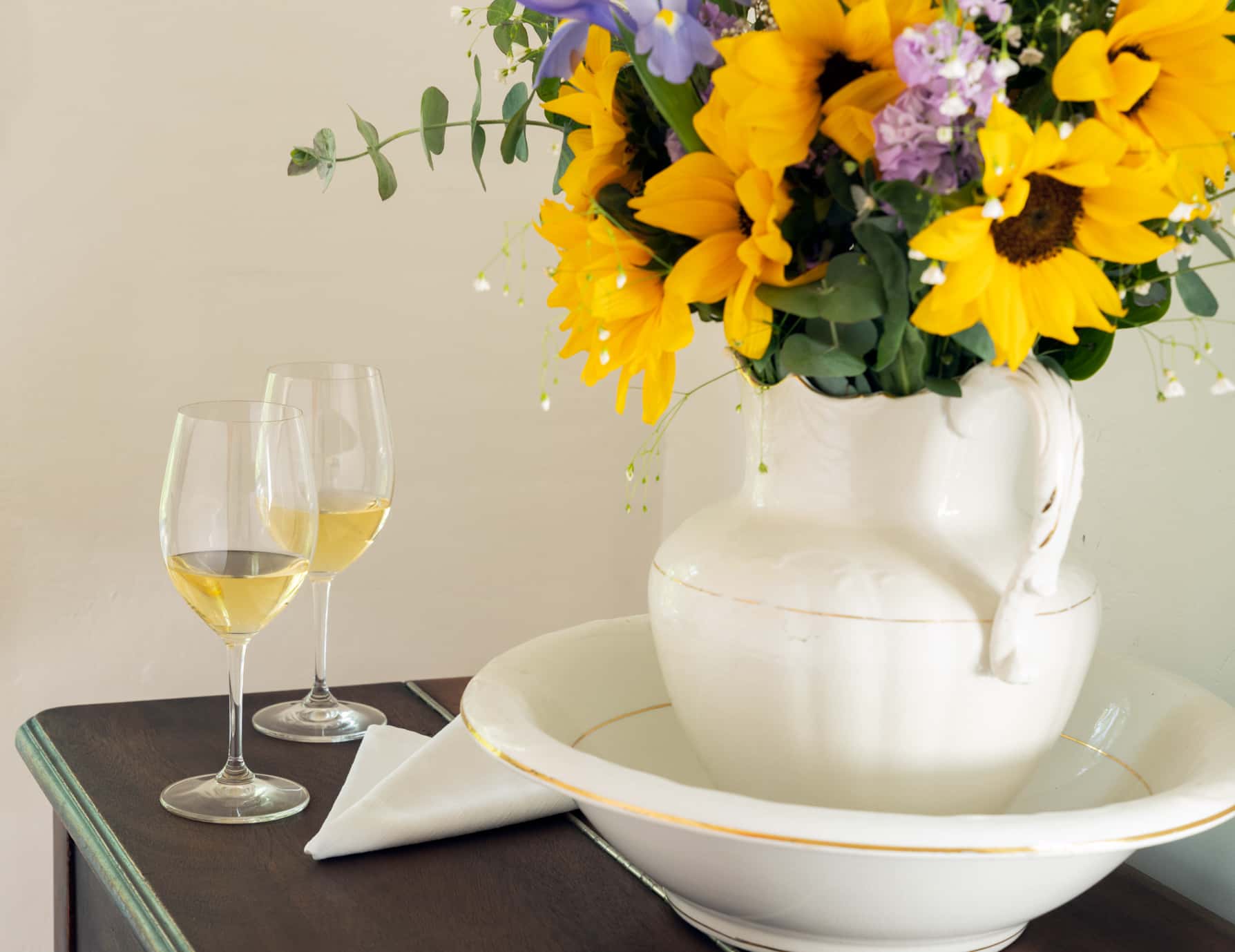 A vase of flowers and two glasses of white wine