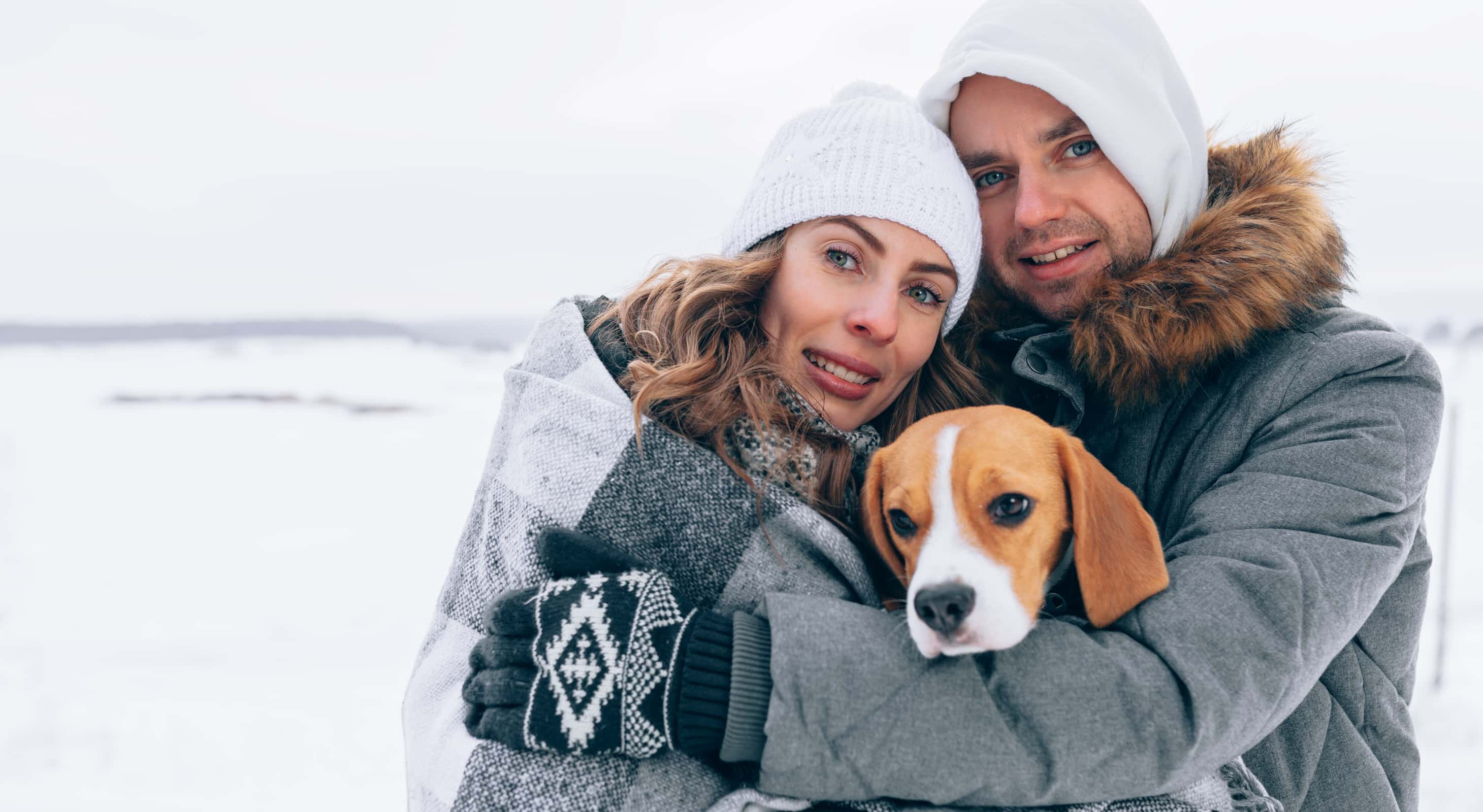 Couple and their dog bundled up together in the winter