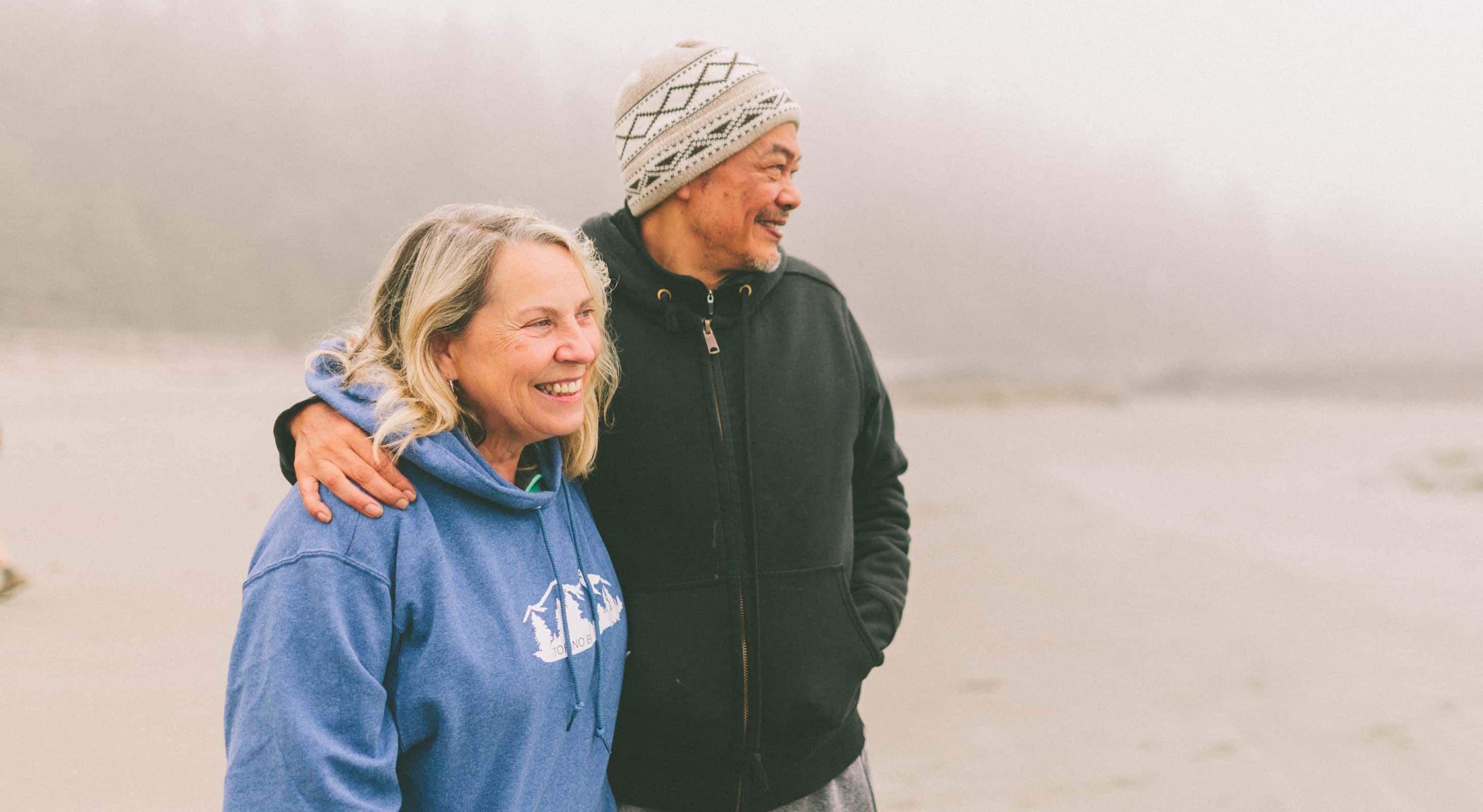 Older couple standing on a beach in the fog