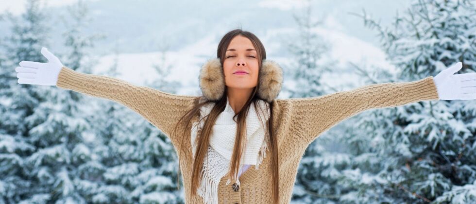 woman with spread arms relaxing in winter forest