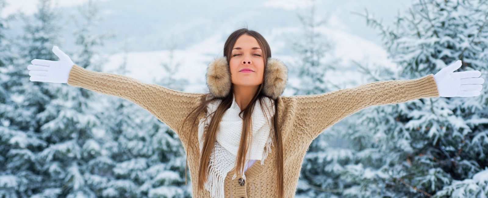 woman with spread arms relaxing in winter forest