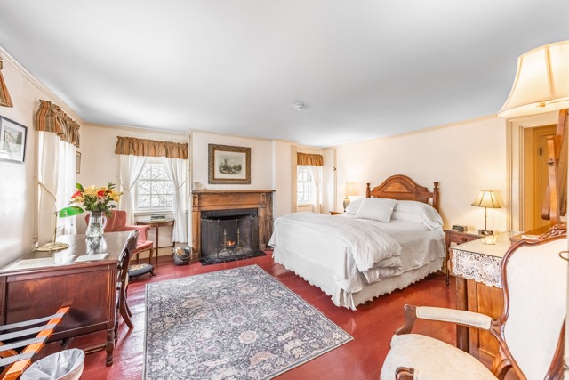 Full size bedroom with fireplace, area rug, desk and chairs