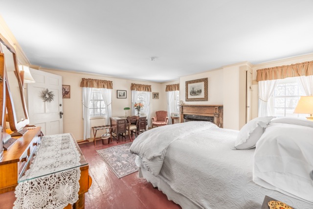 Room 5 with a king bed a seating area and fireplace and hardwood floors with an area rug