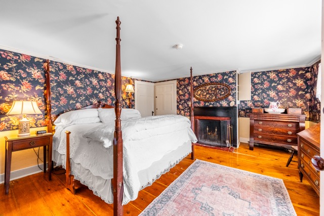 King size bed with end table, area rug, dresser and fireplace