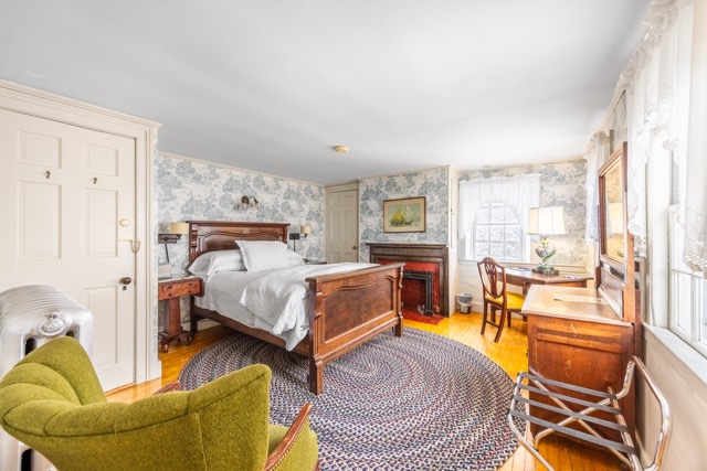 Queen bedroom with oval rug, dresser and desk