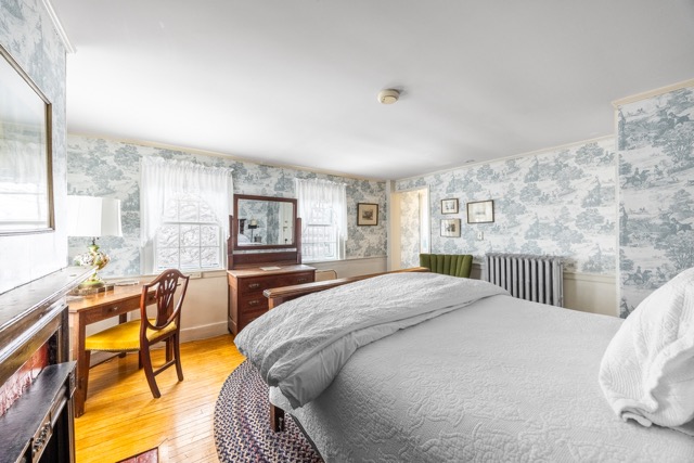 Room 6 with a queen bed two end tables and hardwood floors