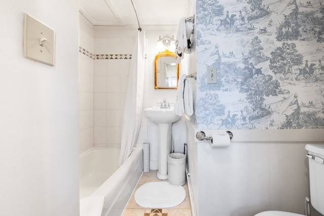 Room 6 bathroom with a small sink and mirror and a tub shower combination