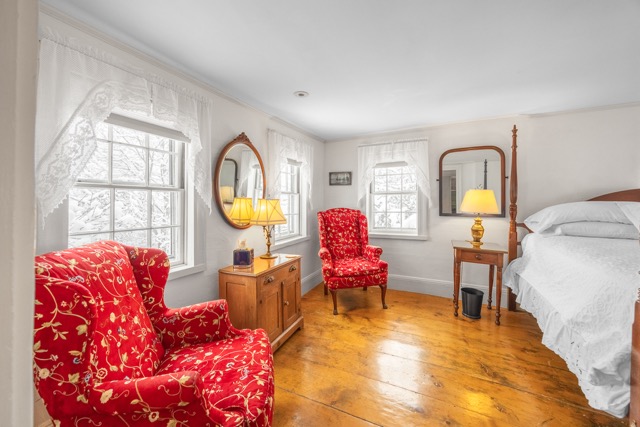 Room 8 with two chairs and a small cabinet set against a wall with large windows