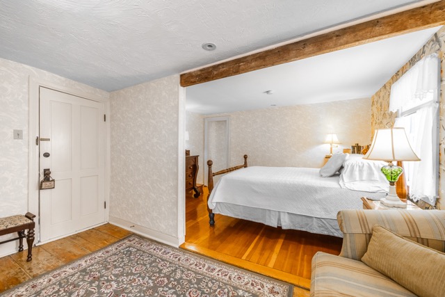 Room 3 bed and seating area with area rug and dresser