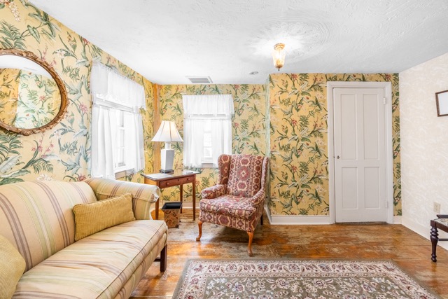 Sitting area with couch, chair, end table, rug and windows