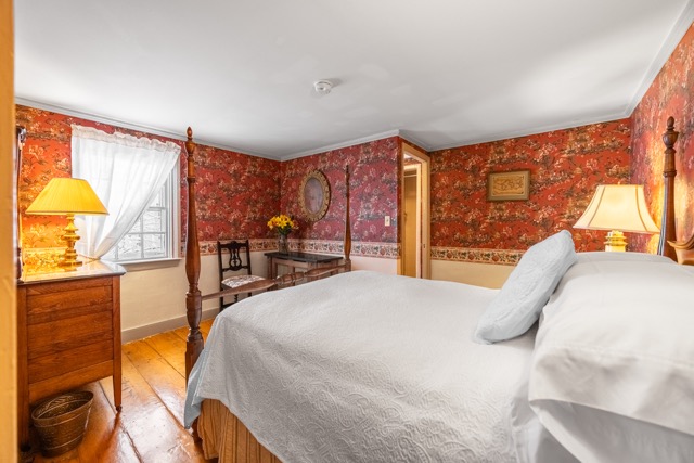 Room 2 with full bed, red floral wallpaper, window and dreser